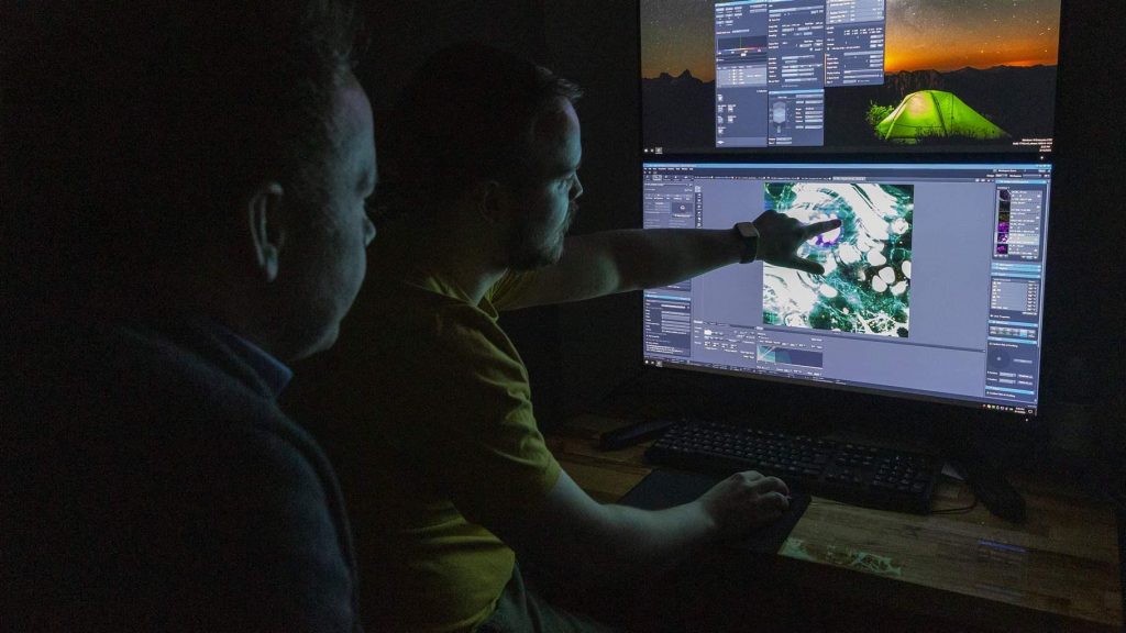 Cleves and a team member observe images of a coral polyp fluorescing